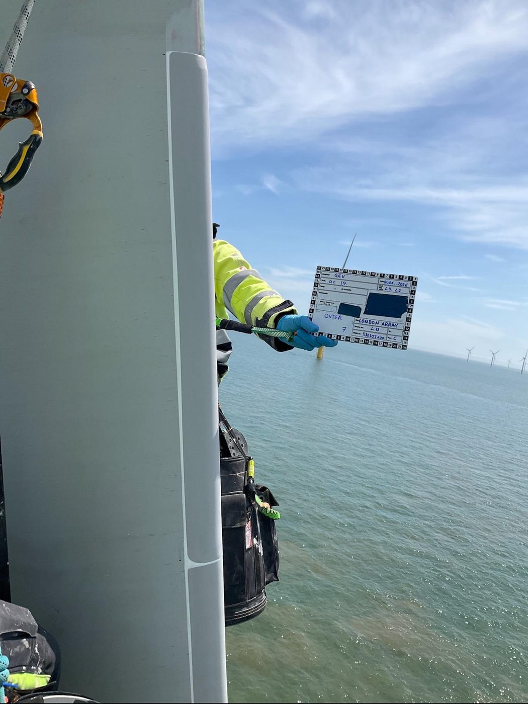 Technik dokumentuje stan łopaty turbiny wiatrowej podczas serwisu offshore